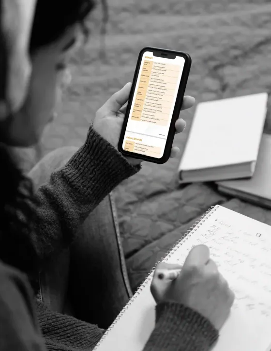 Student studying the Worddemy vocabulary eBook on a phone and taking notes
